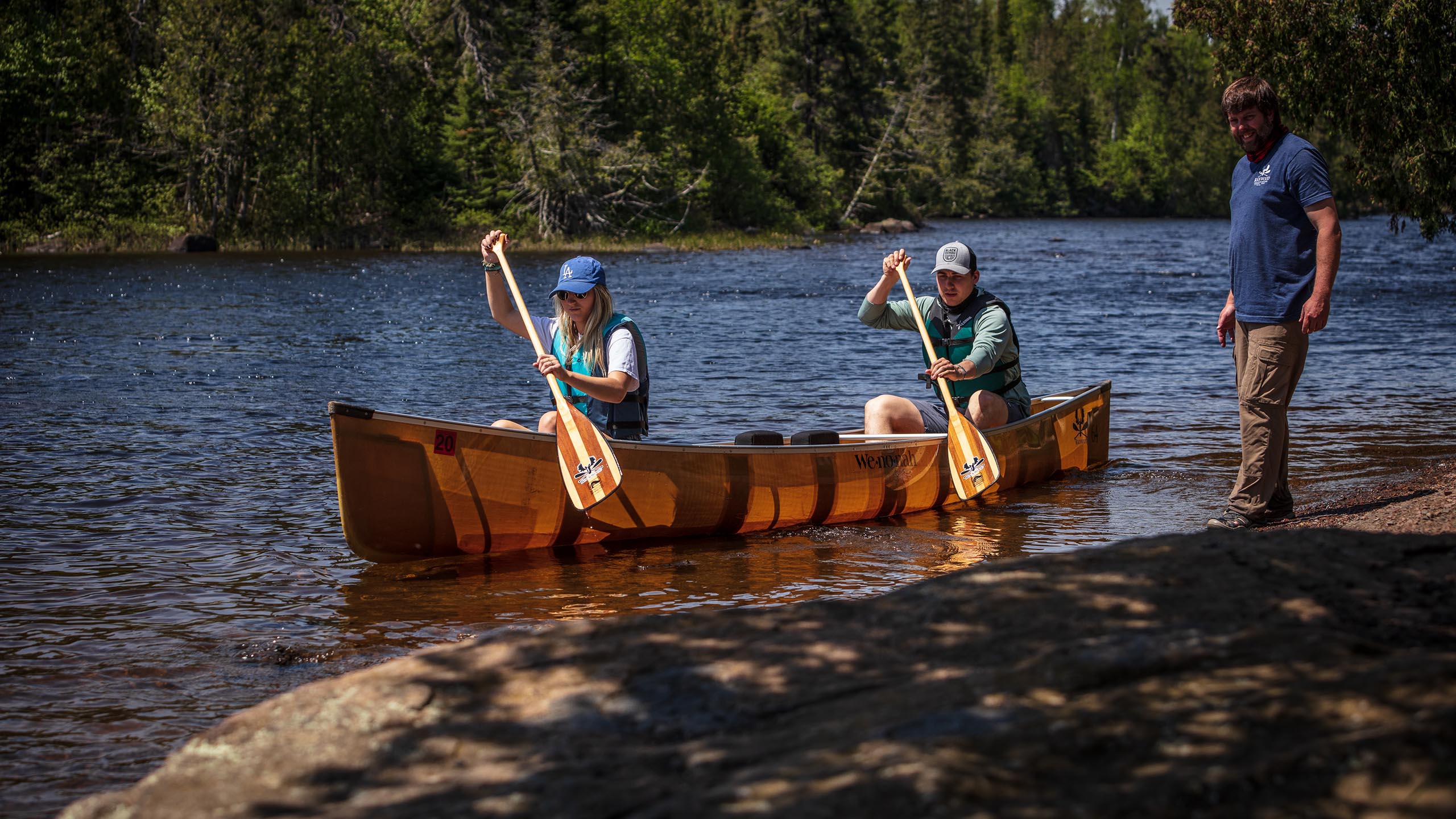 outfitter helping two people enter the boundary waters in a kevlar canoe
