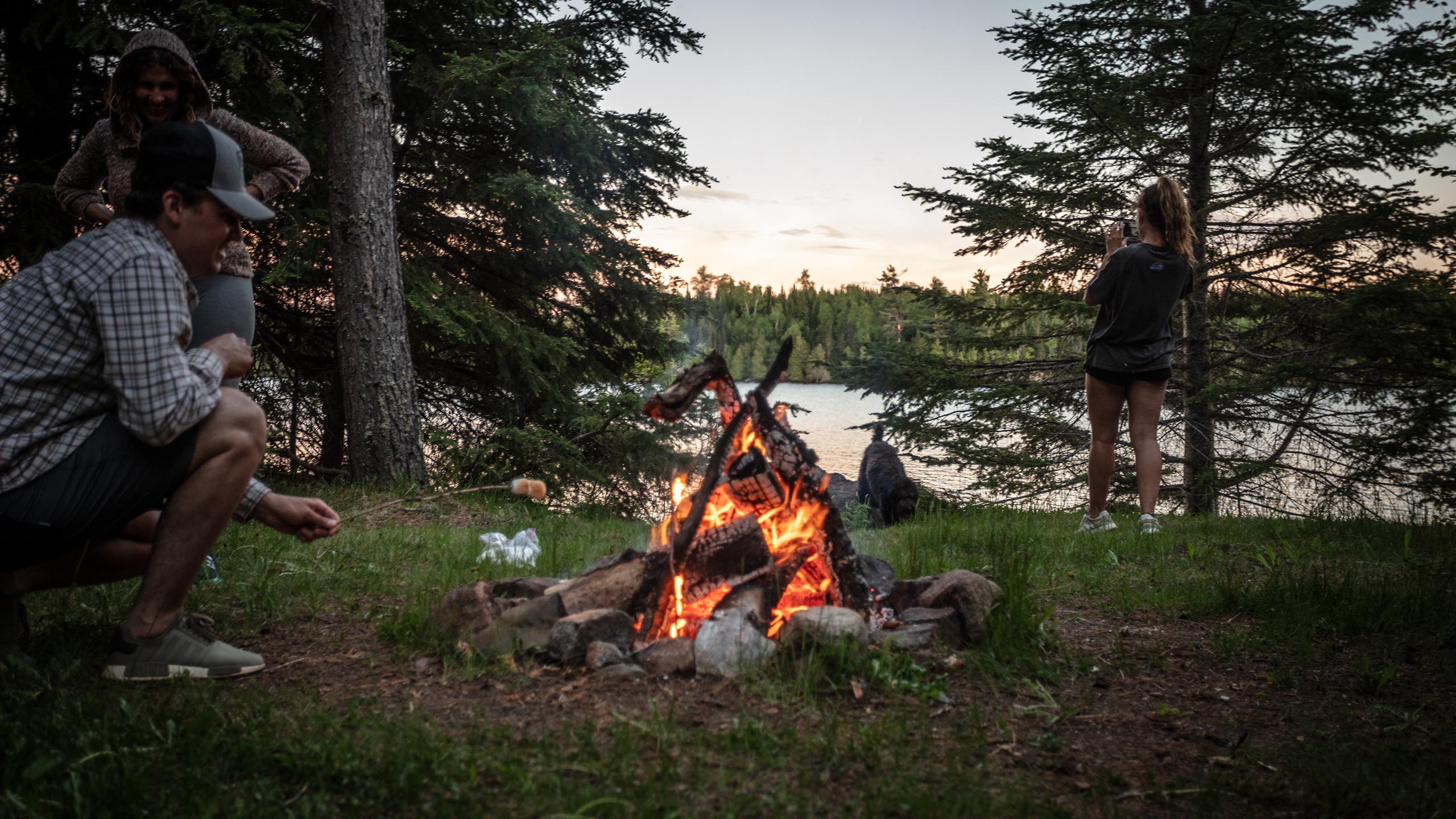 three people enjoying a campfire near the boundary waters